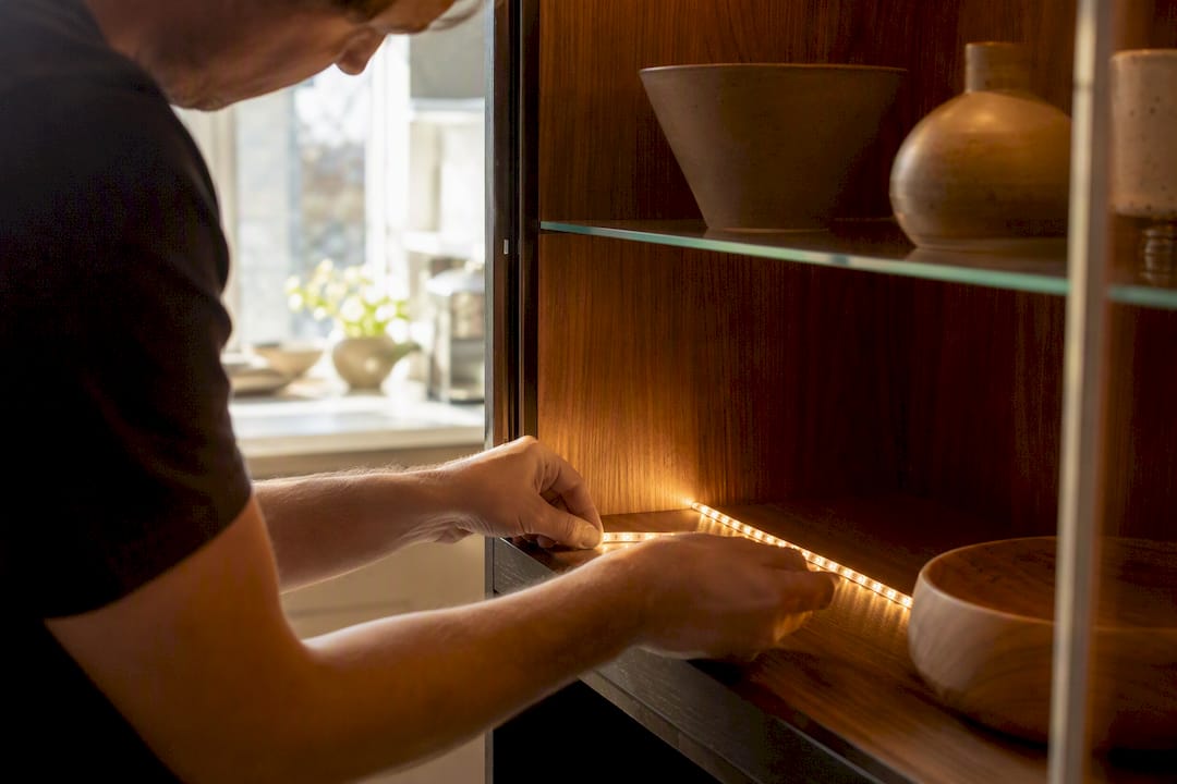 Hands installing LED strip inside display cabinet