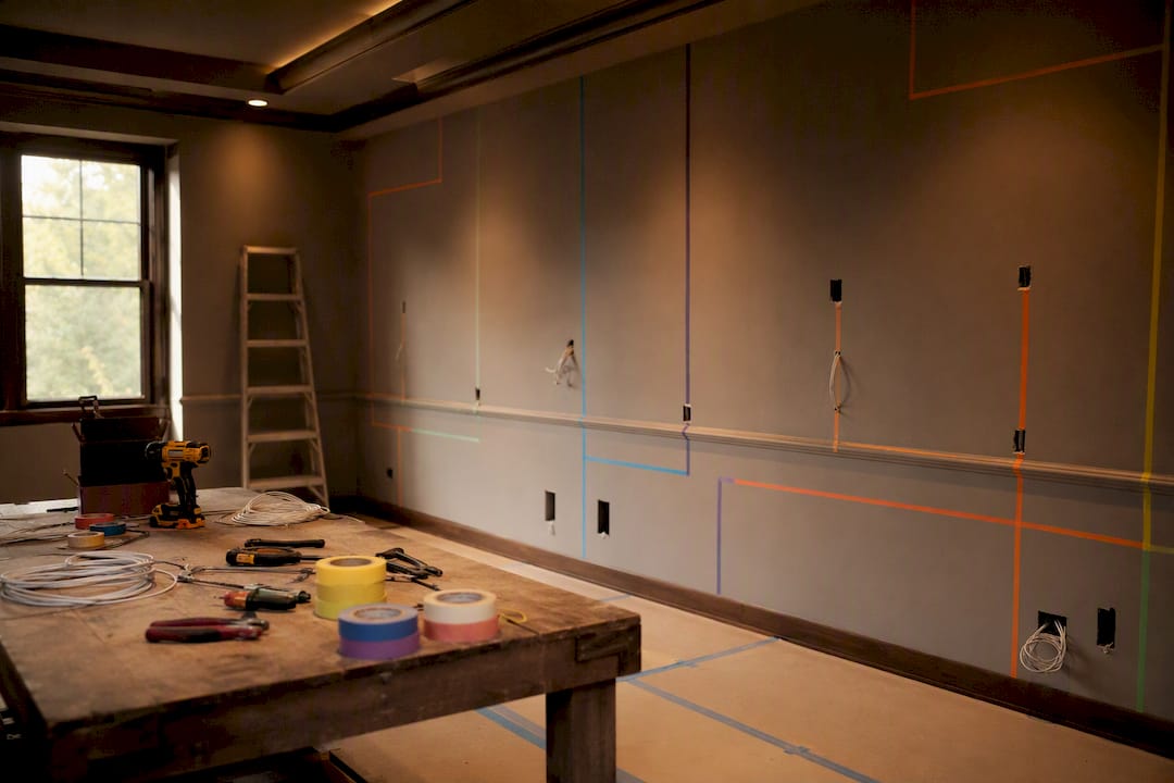 Home theater wall with taped lighting zones and wiring tools