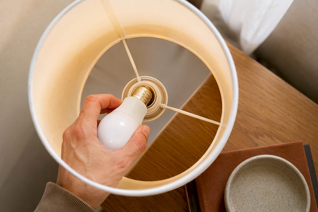 Hand installing a smart bulb in lamp