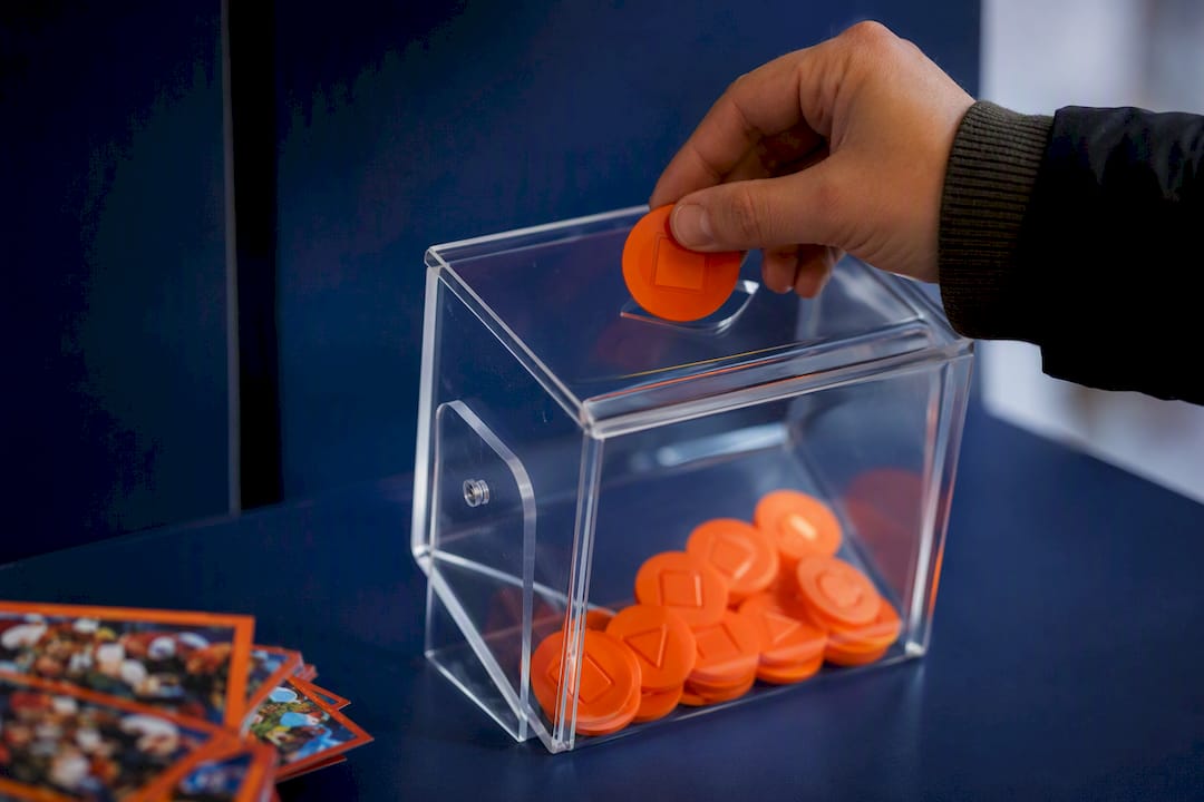 Hands inserting tokens into raffle entry box