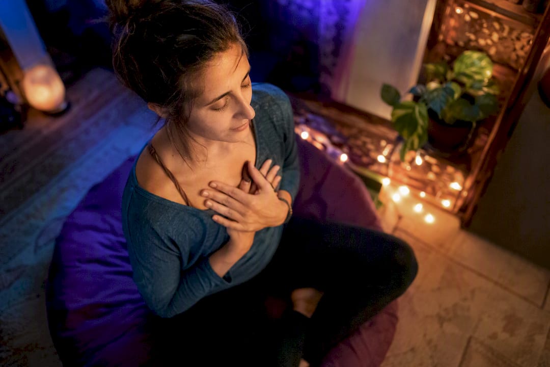 Person cupping ear in meditation with incense