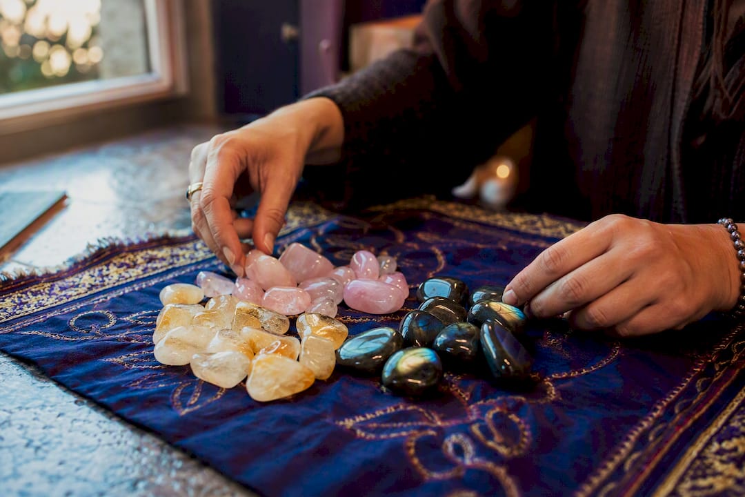 Hands arranging healing crystals on table
