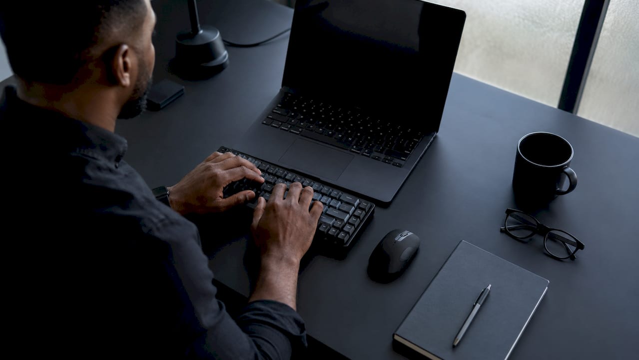 Hands typing and taking notes on marketing tasks