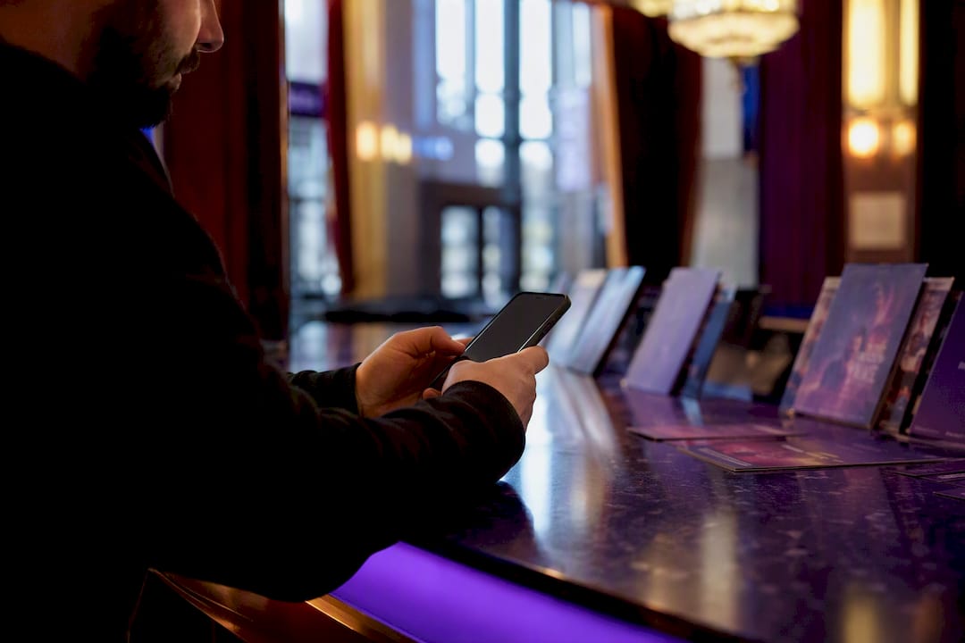 Hands holding phone at theater counter