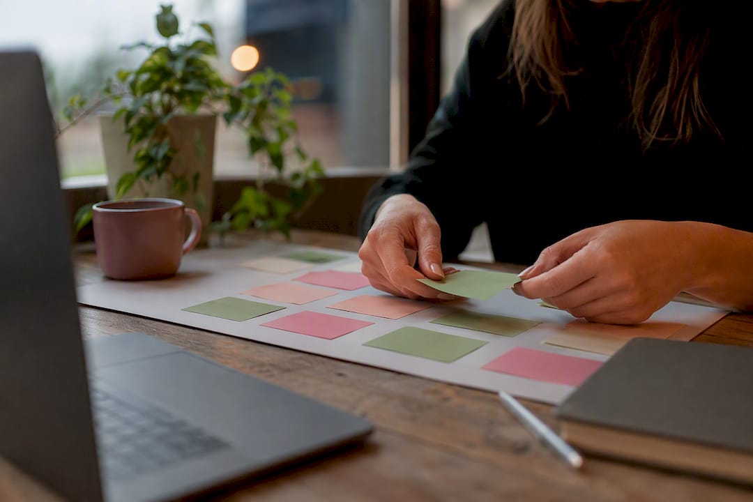Hands arranging sticky notes on desk