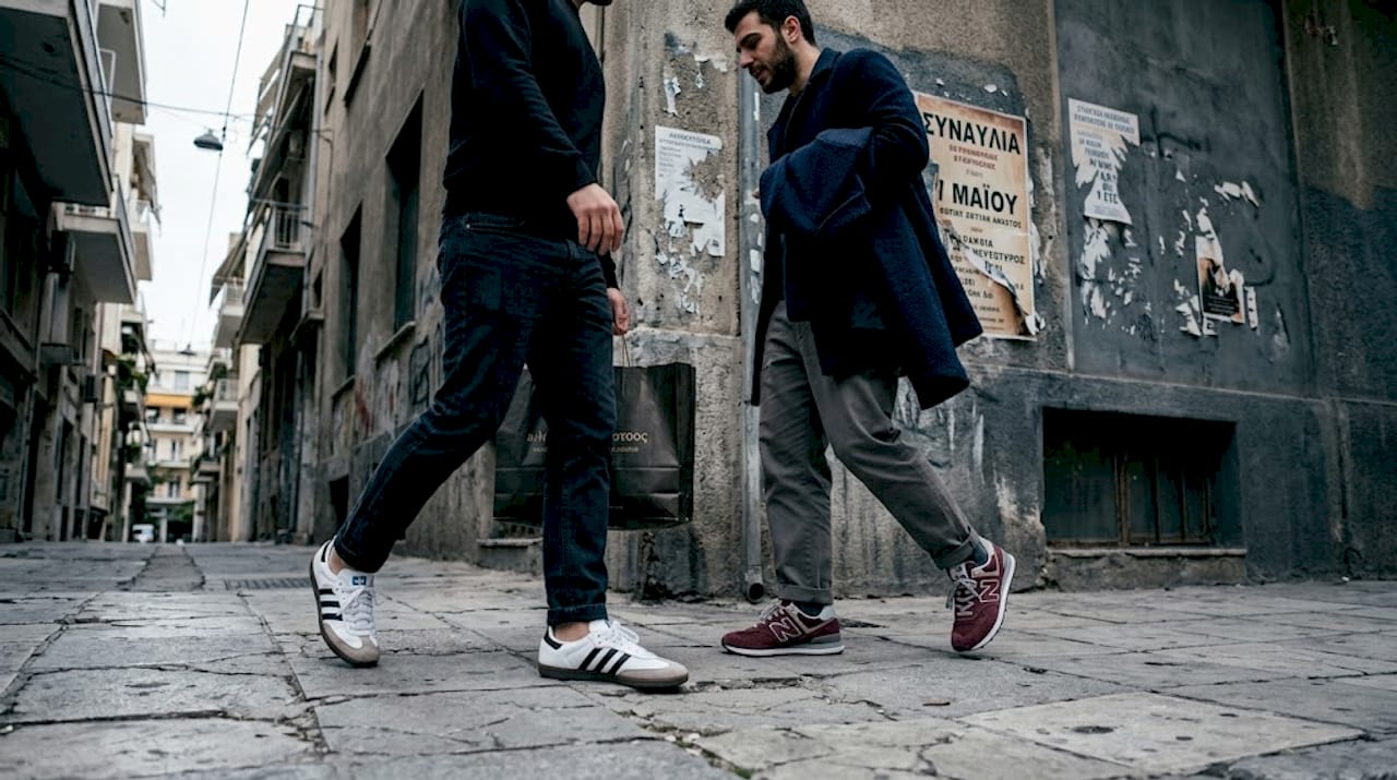 Δύο άντρες με ρετρό αθλητικά περπατούν σε έναν πολυσύχναστο δρόμο της πόλης.