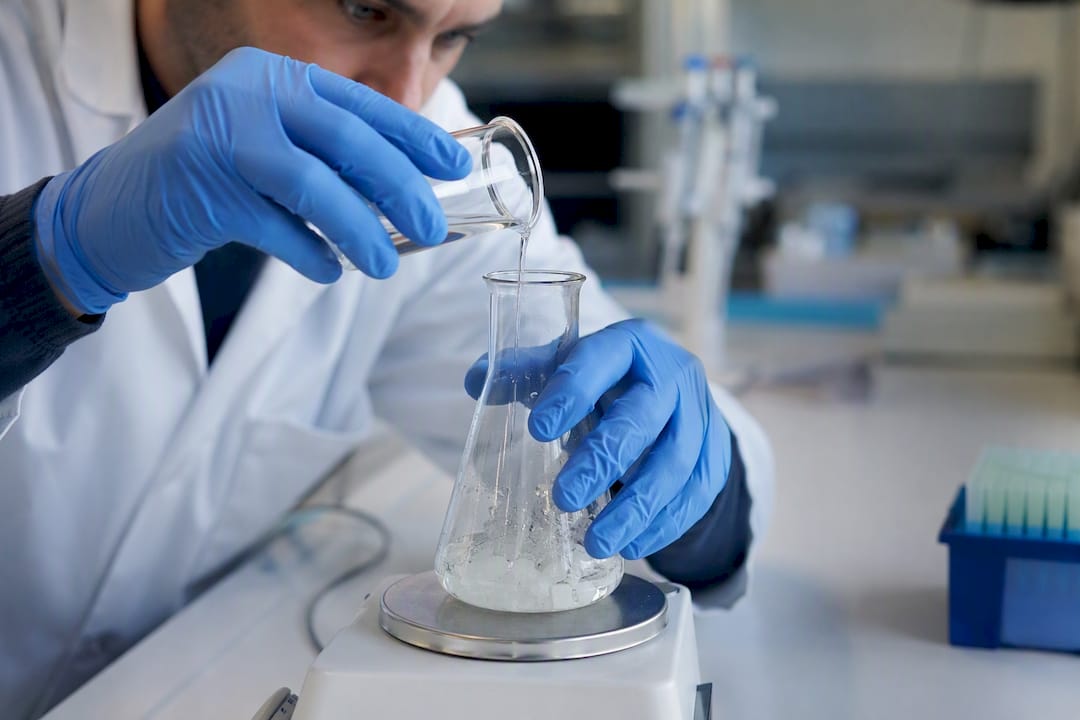 Técnico de laboratorio añadiendo agente solubilizante a muestra de proteína