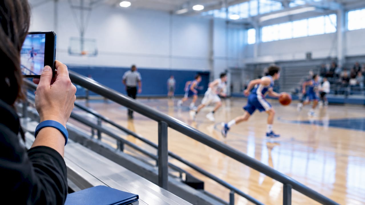 Parent filming youth basketball game