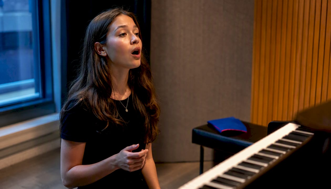 Teen singer matching pitch beside keyboard