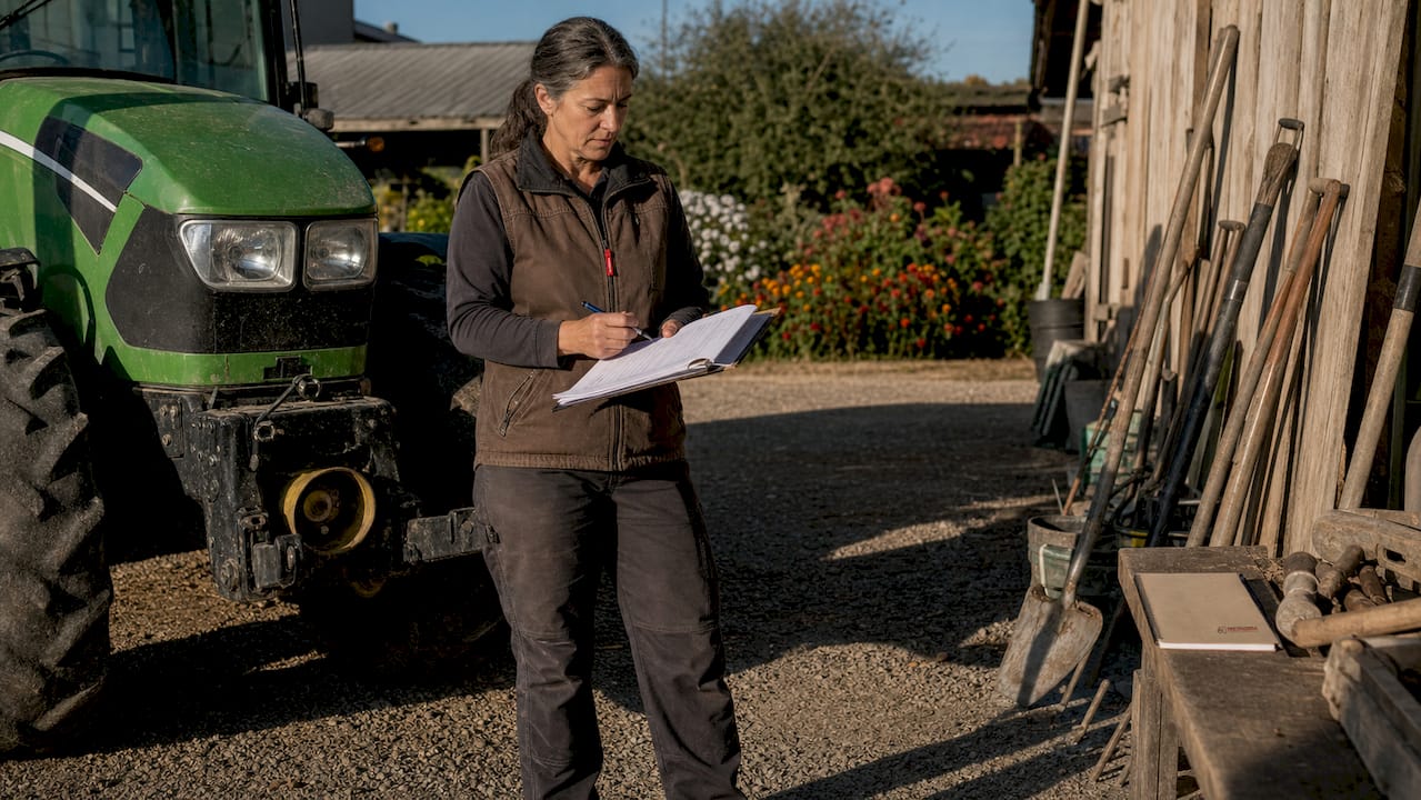 Hands checking tractor inspection form outdoors