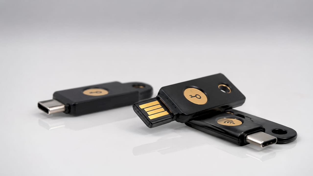 Три различни модела YubiKey защитни ключове, представени на черен фон