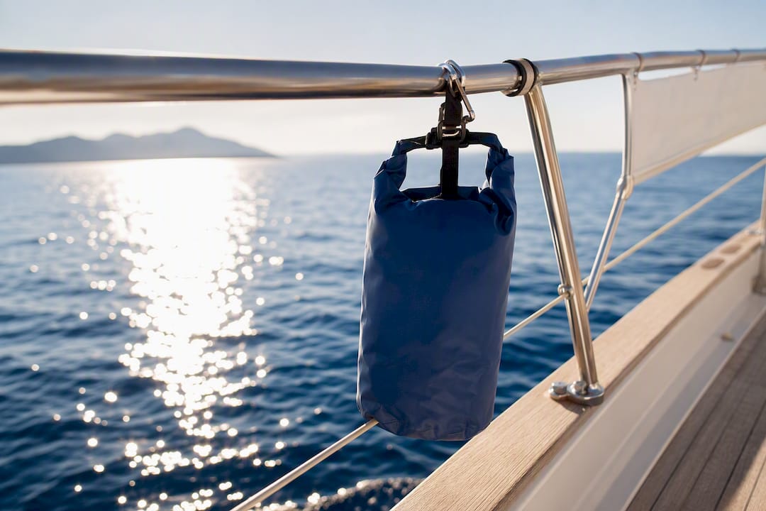 Dry bag hanging from yacht railing over ocean