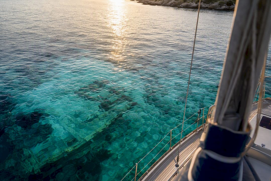 Sailing yacht over clear water revealing coral and shipwreck remains
