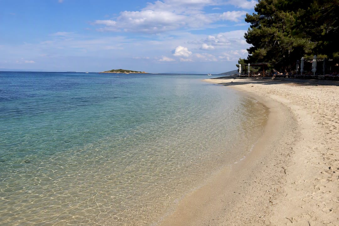 Shallow sandy shore and small island offshore at Karidi