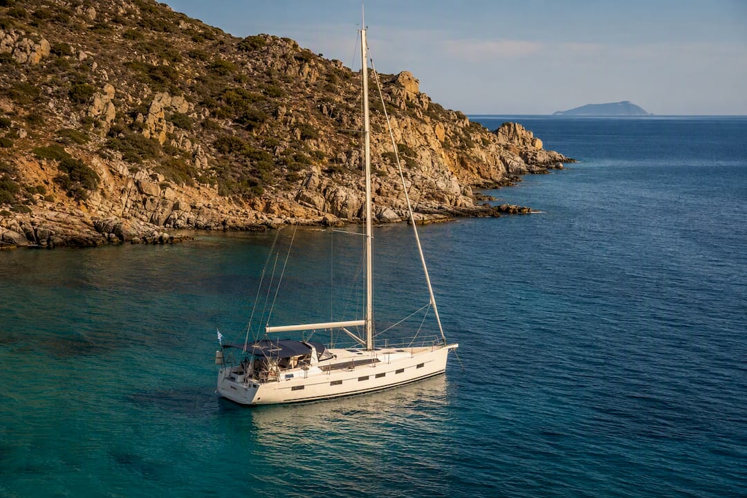 Sailing yacht anchored near rocky island coast