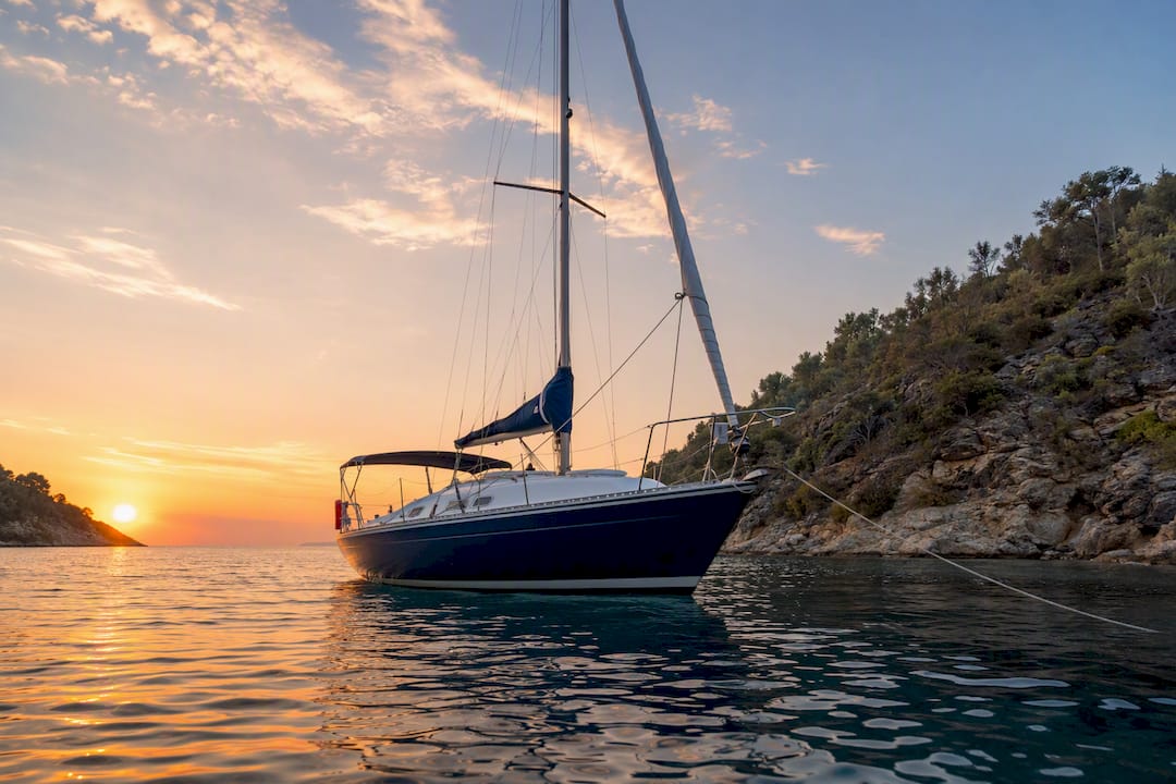 Sailing boat moored in calm bay at sunset
