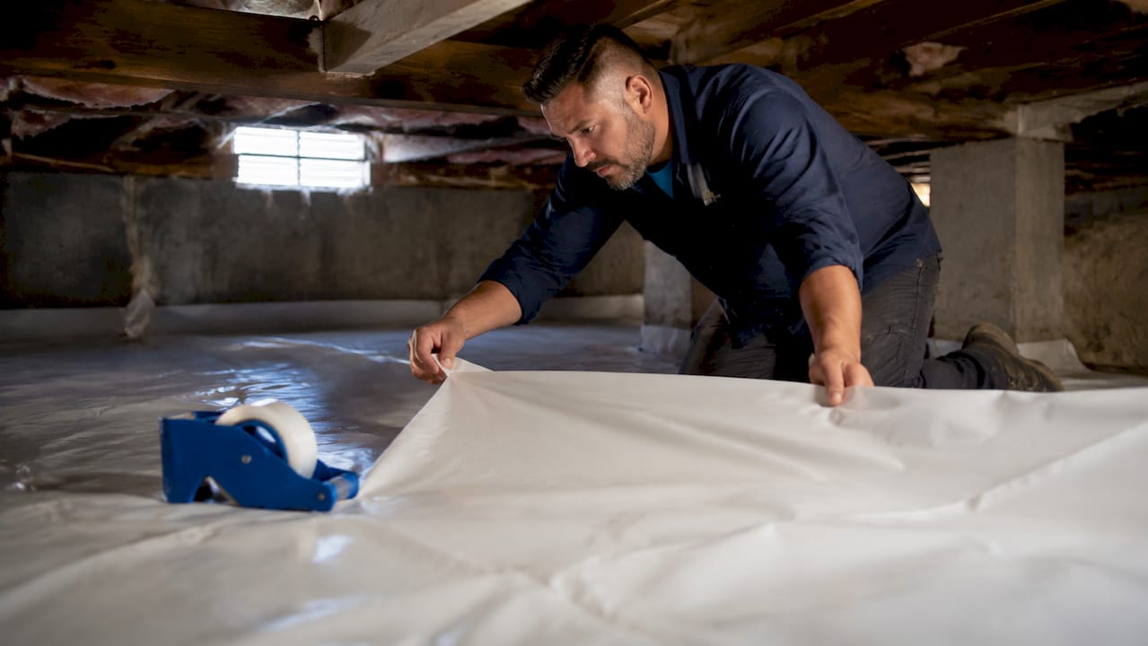 Contractor installing crawl space liner and sealant
