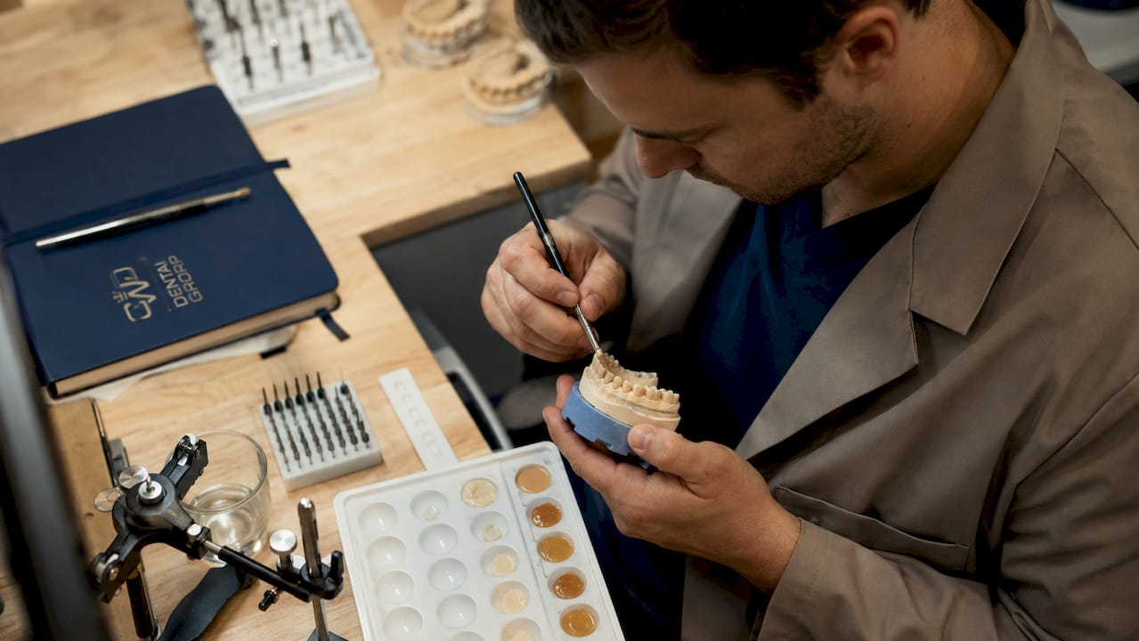 Dental technician applying bonding resin on mold