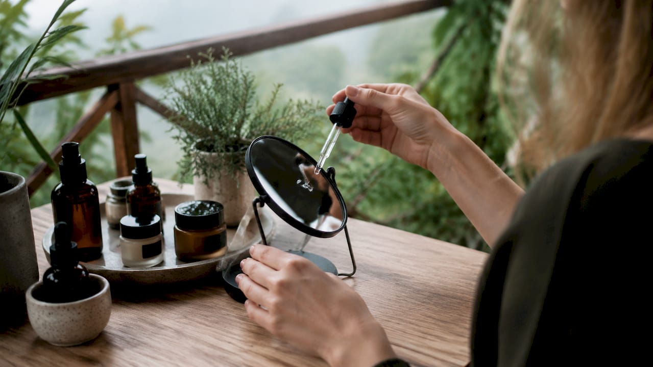 Λεπτομέρεια χεριών που εφαρμόζουν serum στο πρόσωπο