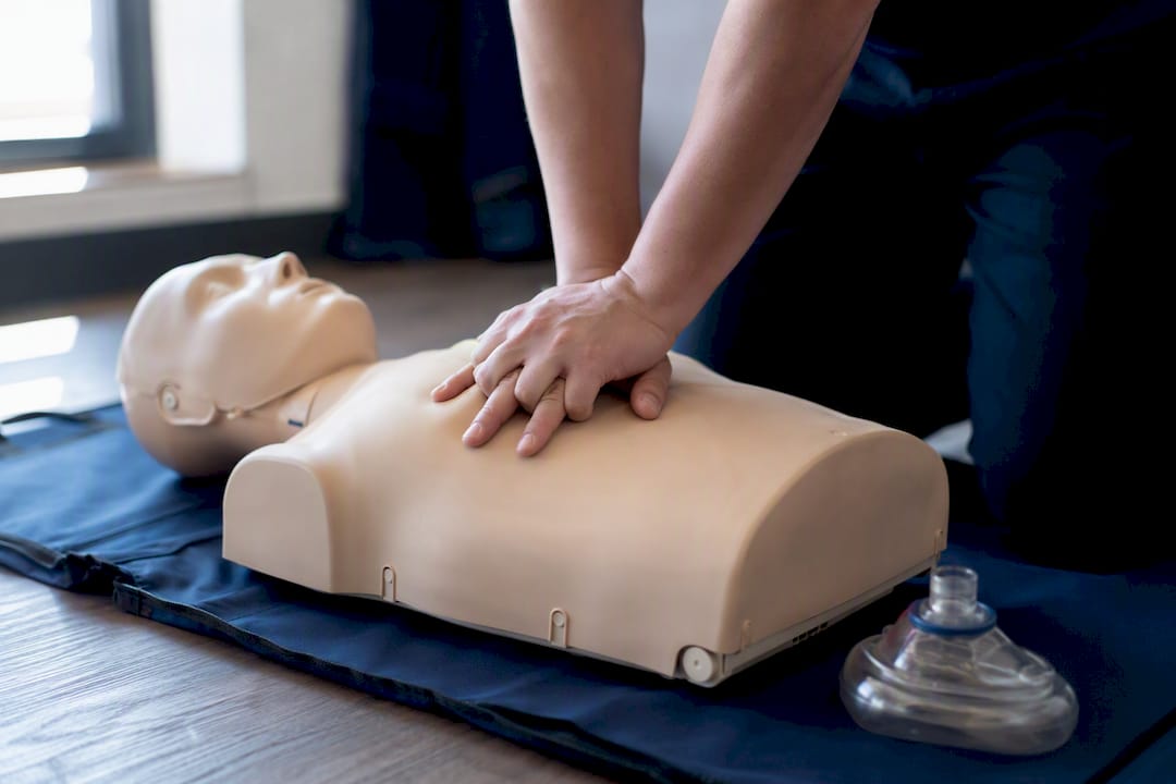 Hands practising CPR on a training mannequin