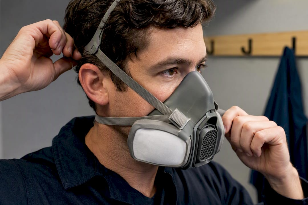 Worker adjusting respirator straps before fit testing