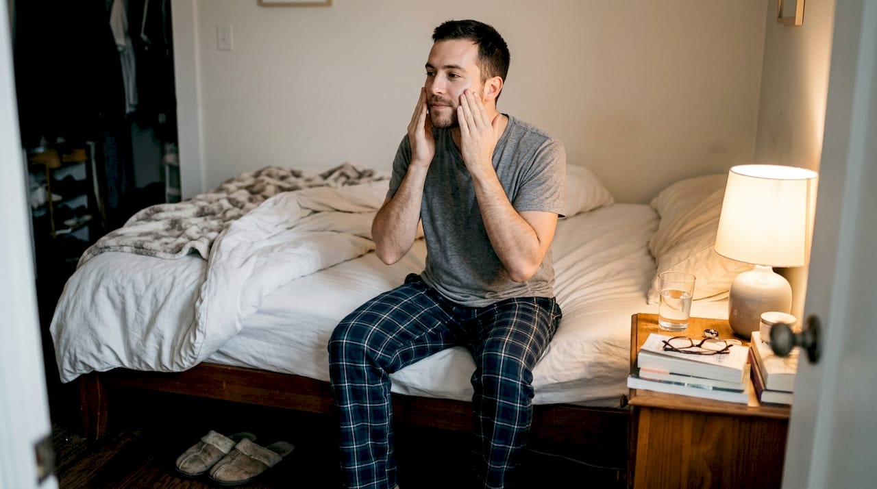 Man applying serum in cozy bedroom evening