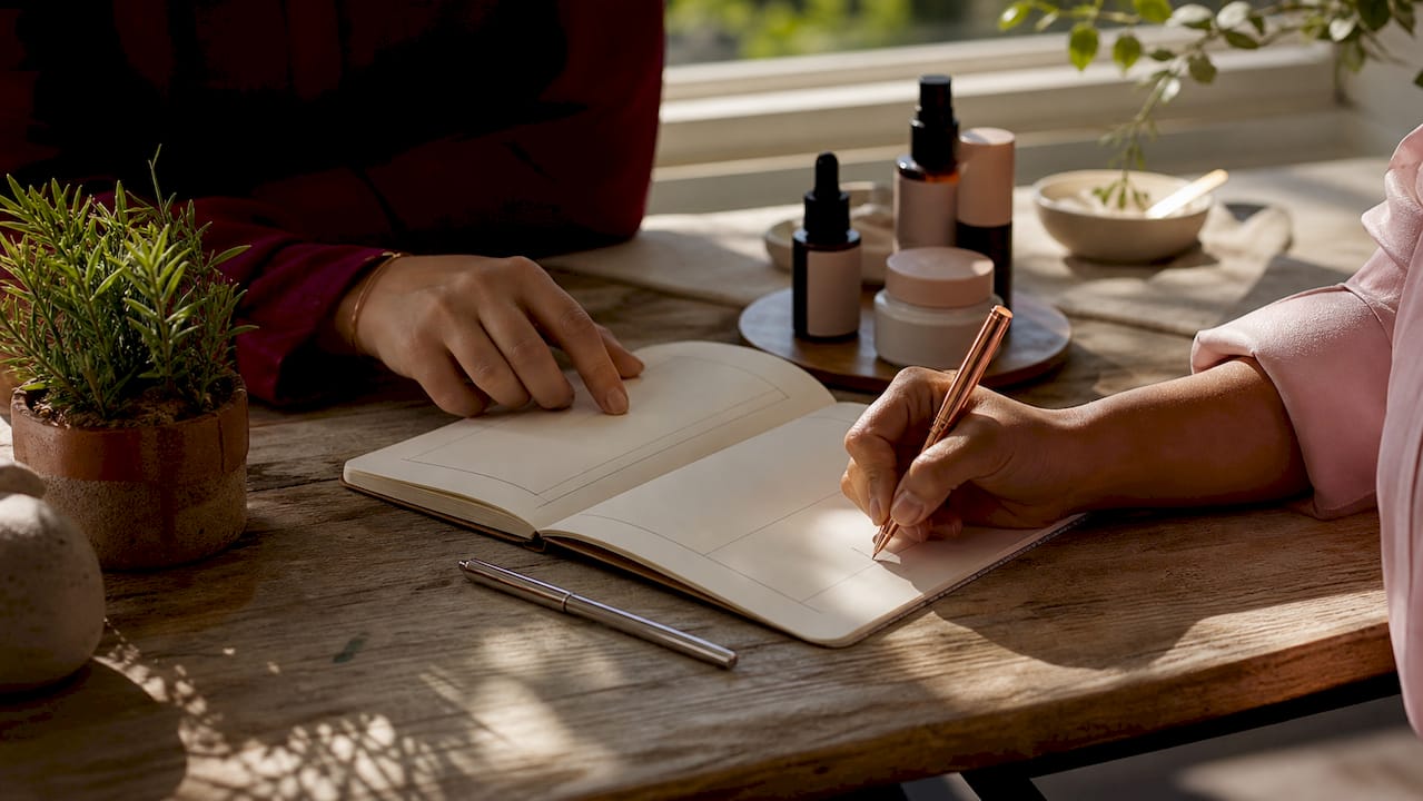 Hands recording makeup reaction notes at desk