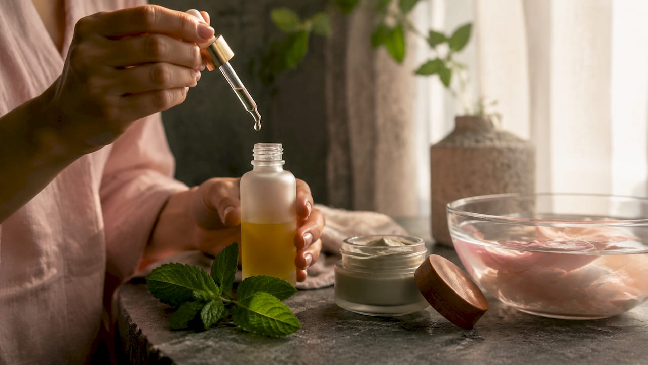 Hands holding dropper bottle of omega oil with golden drop