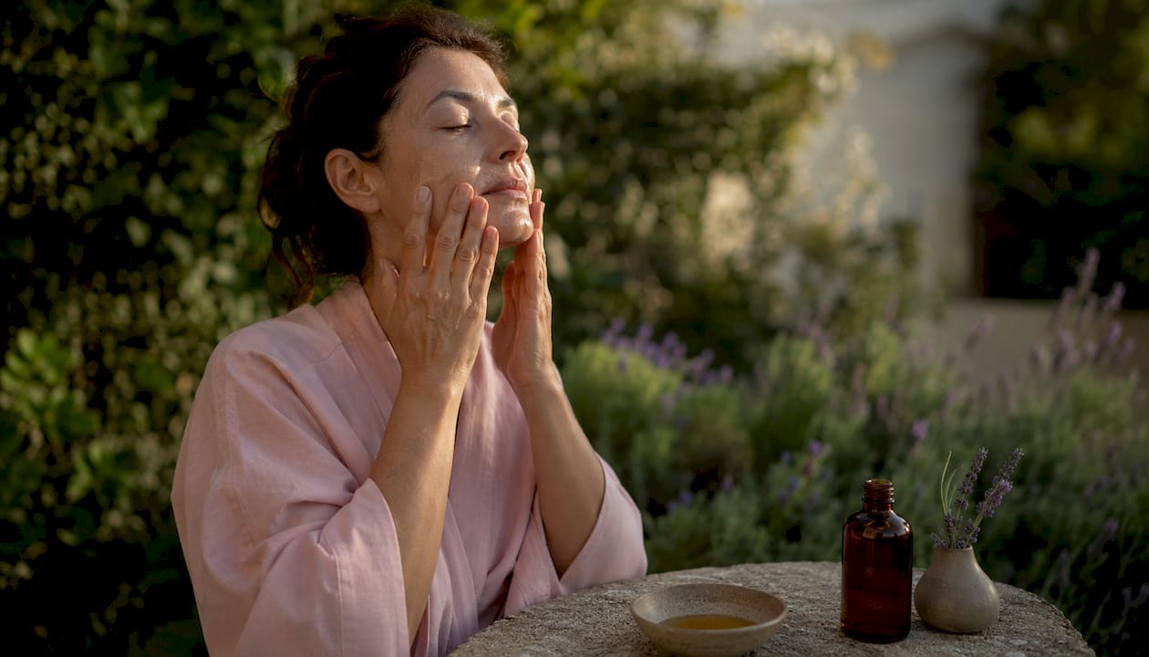 Hands performing facial self-massage with oil