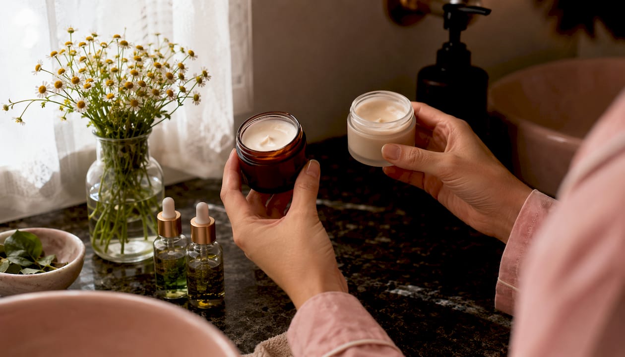 Hands comparing calming skincare jars with botanicals