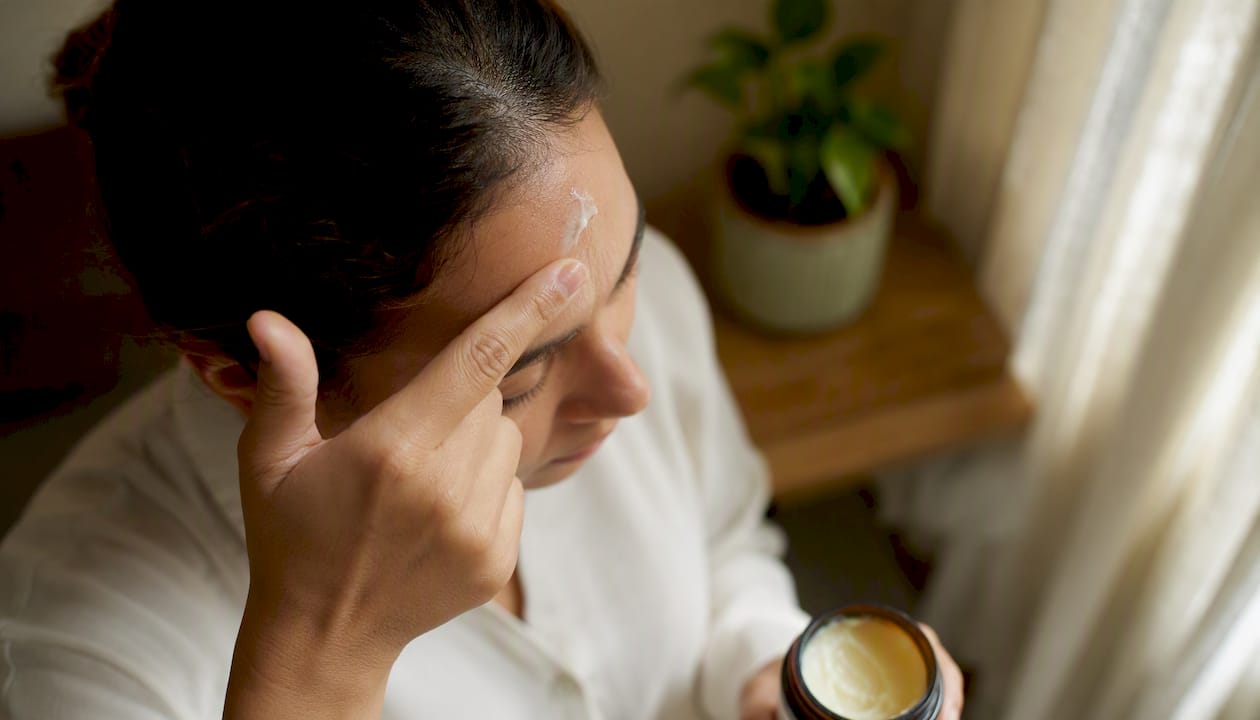 Hand pressing hydrating balm onto dry skin patch