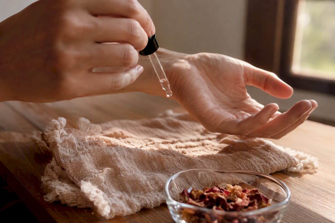 Hand applying clear facial oil drop