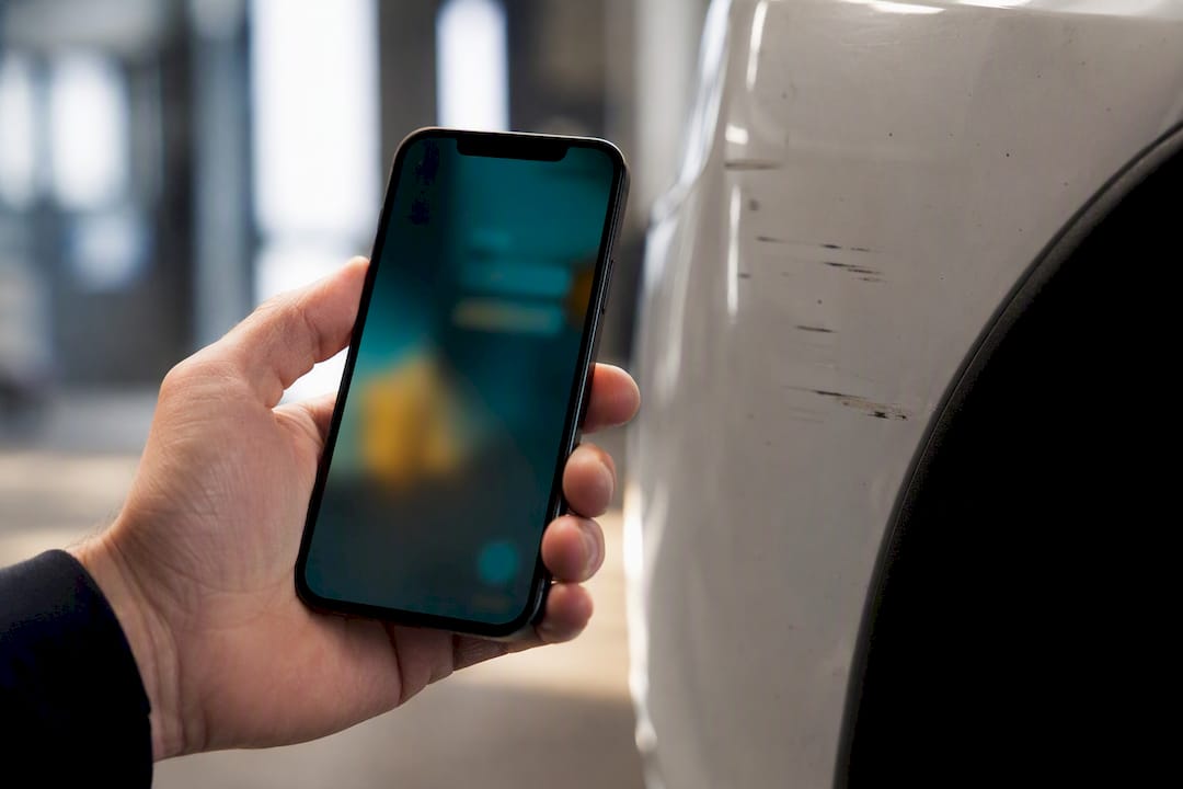 Sjåføren tar bilde av skaden på bilen med mobilen