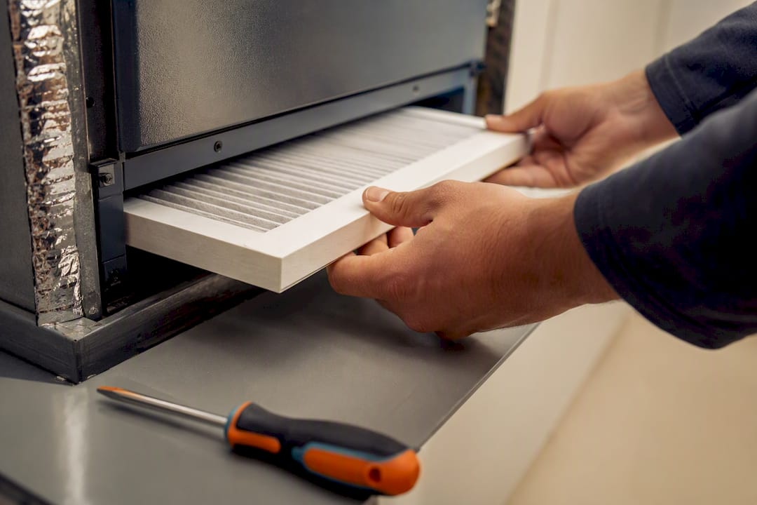 Hands replacing a clean HVAC air filter