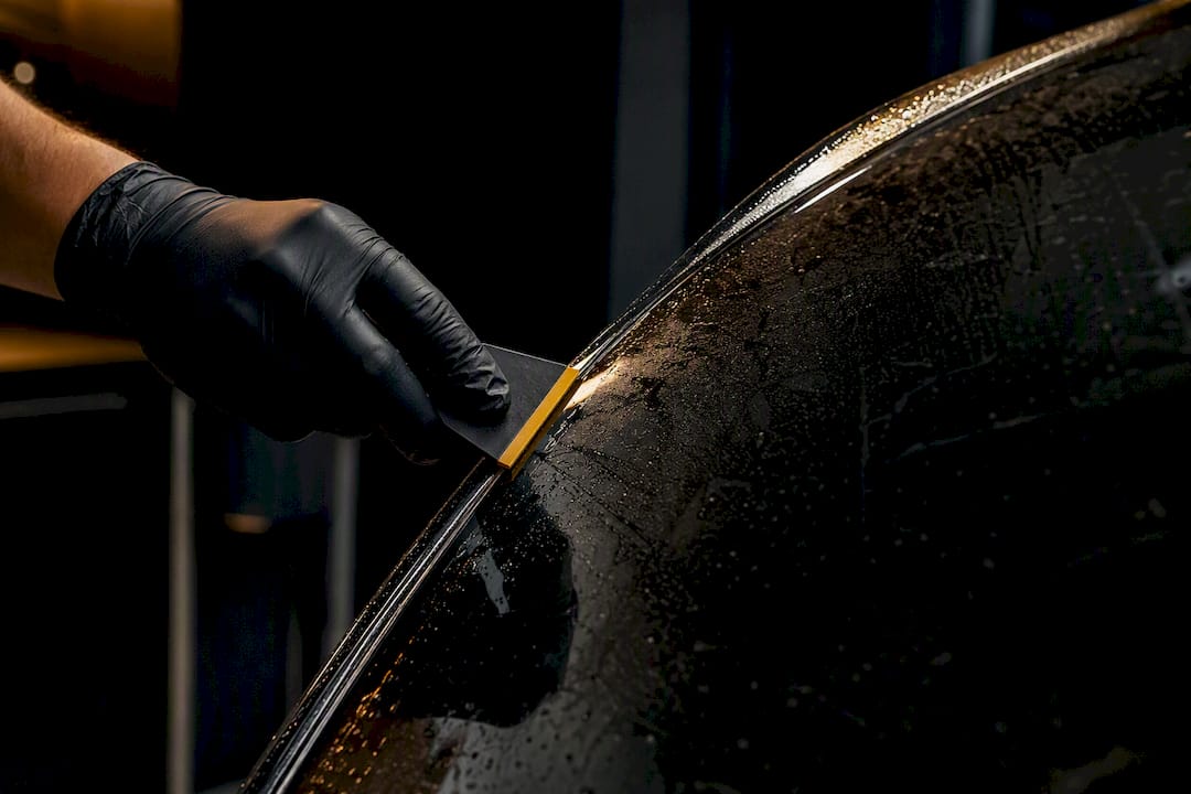 Technician applying film to curved window edge