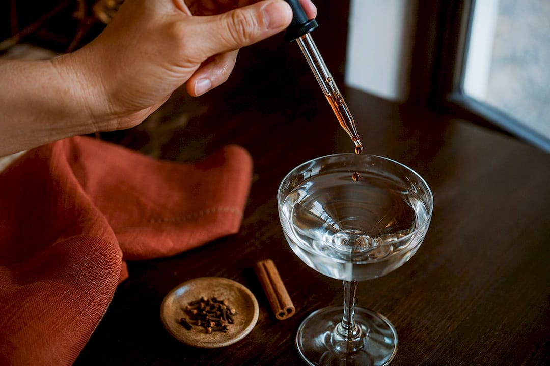 Drops of aromatic bitters entering a gin glass