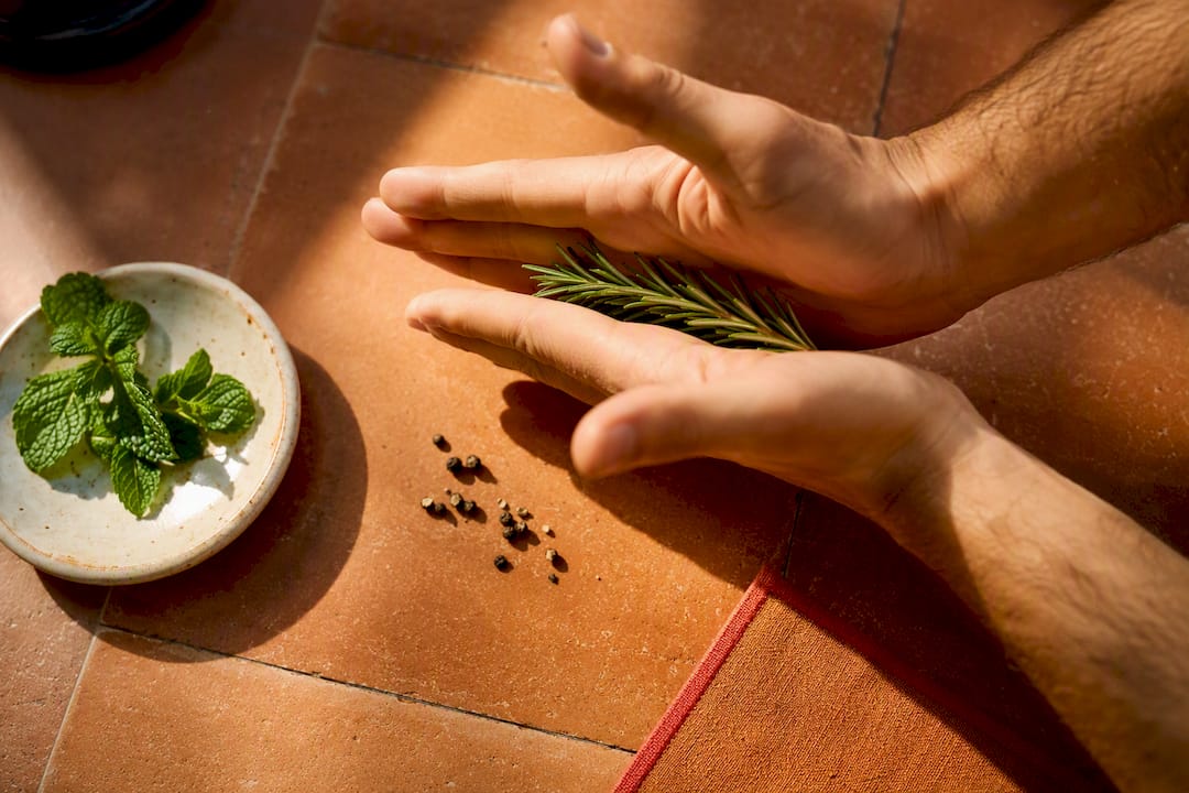 Hands gently releasing rosemary garnish oils