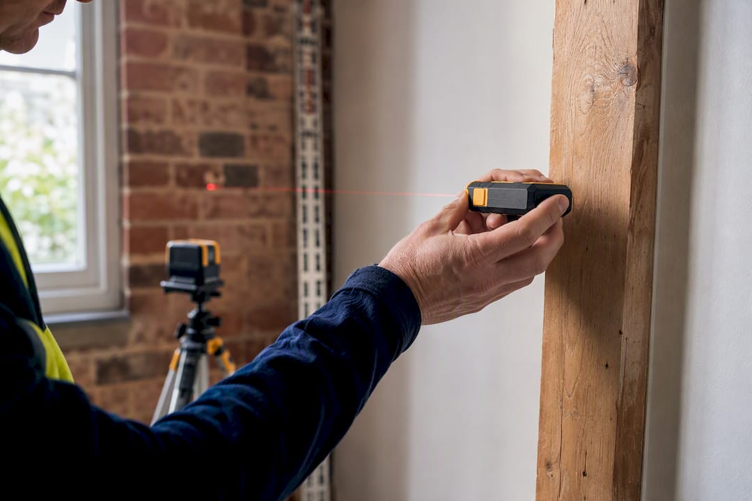 Surveyor checking room dimensions with laser measure