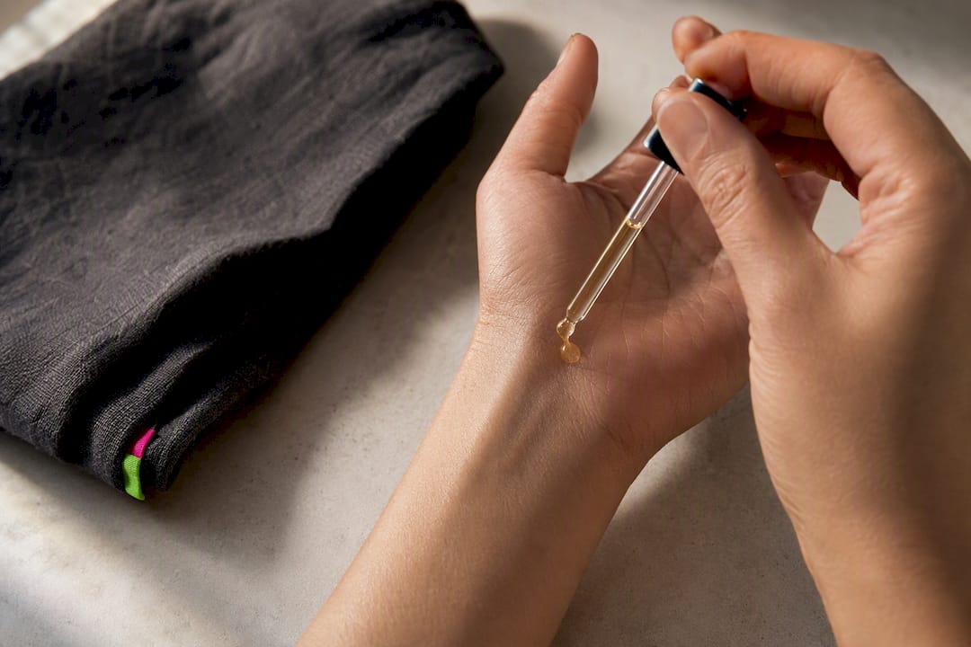 Hands pressing perfume oil onto a wrist