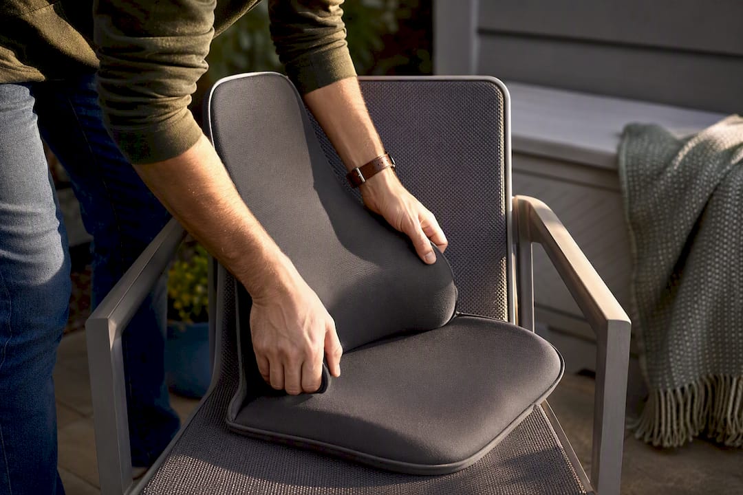Hands placing ergonomic insert in chair