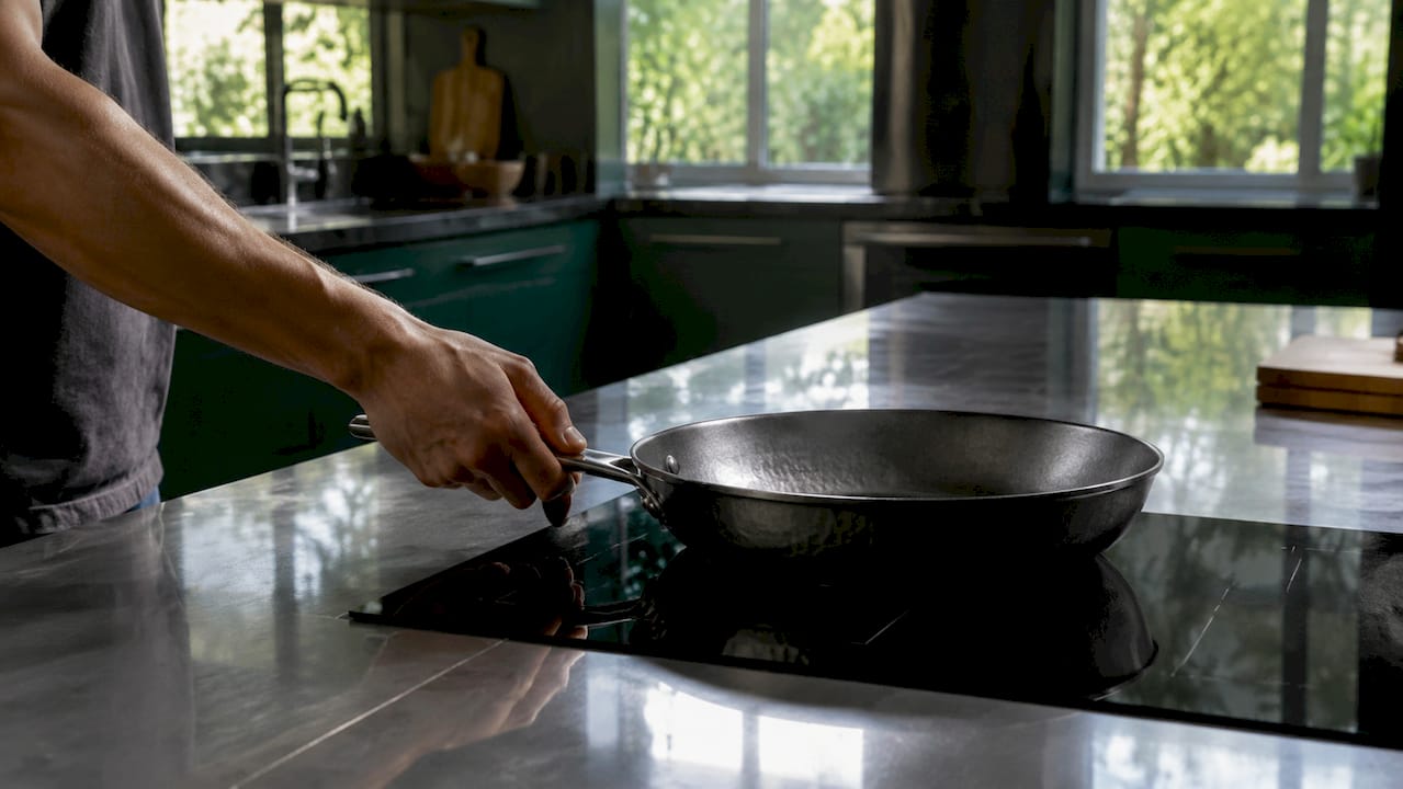 Hand placing carbon steel pan on induction cooktop