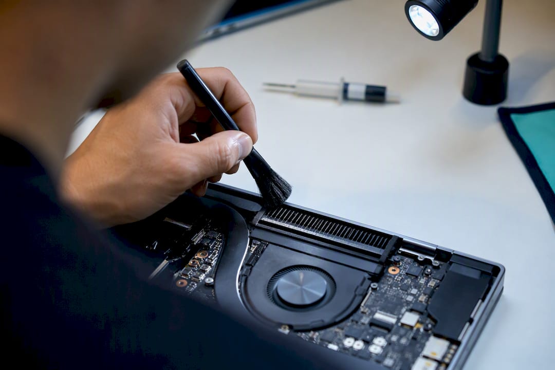 Technician cleaning laptop vent and heat sink