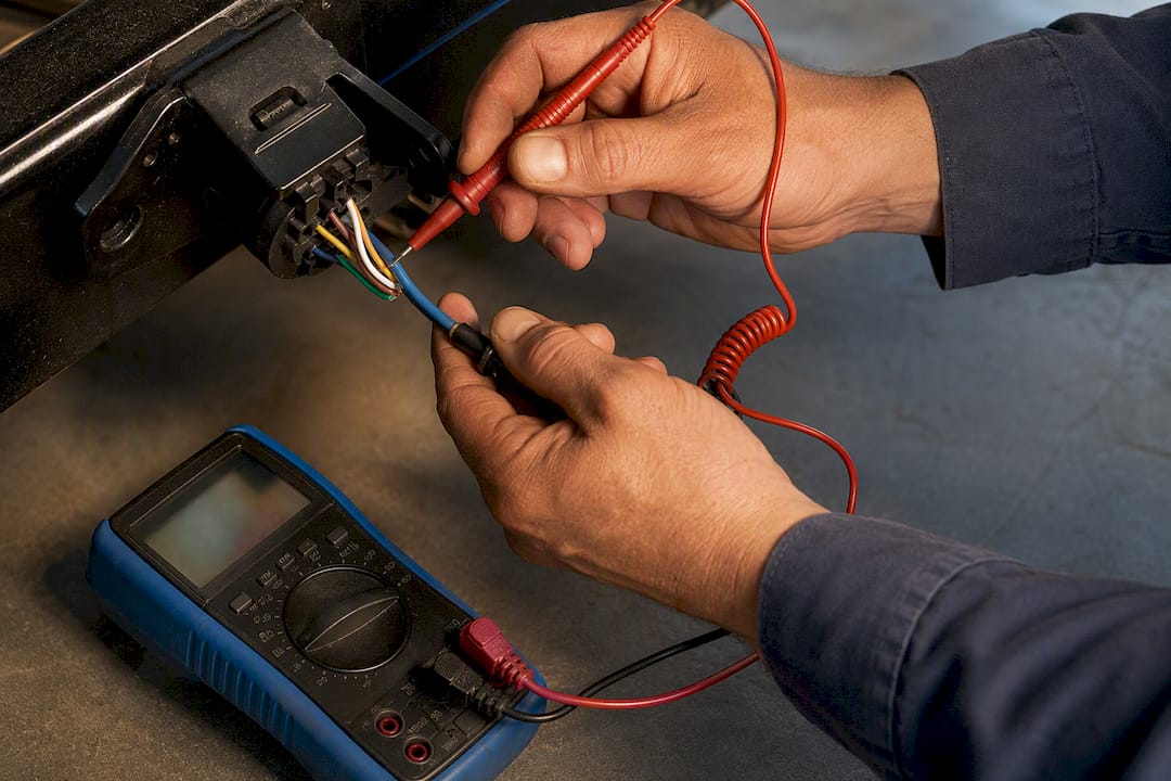 Hands testing trailer brake wire voltage