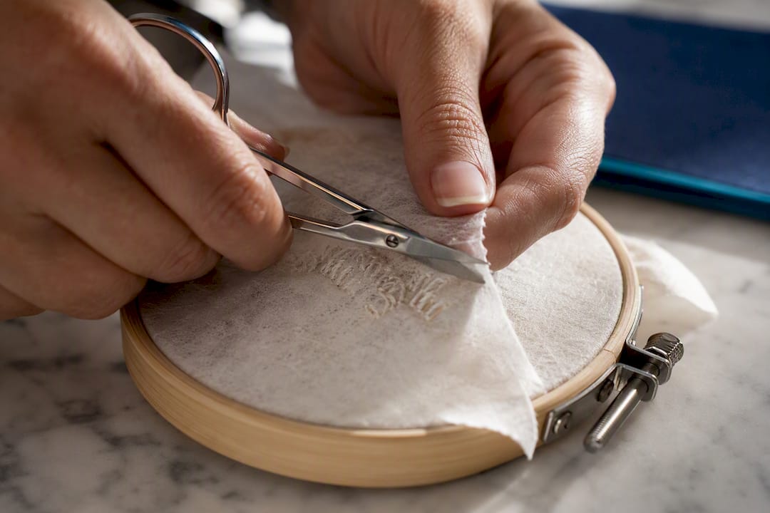 Hands trimming stabiliser from embroidery reverse