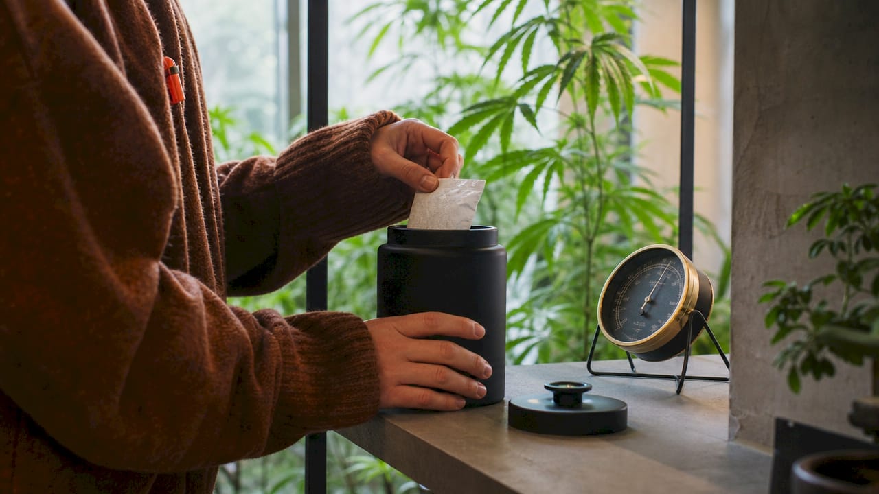 Hands adding humidity pack to cannabis storage jar
