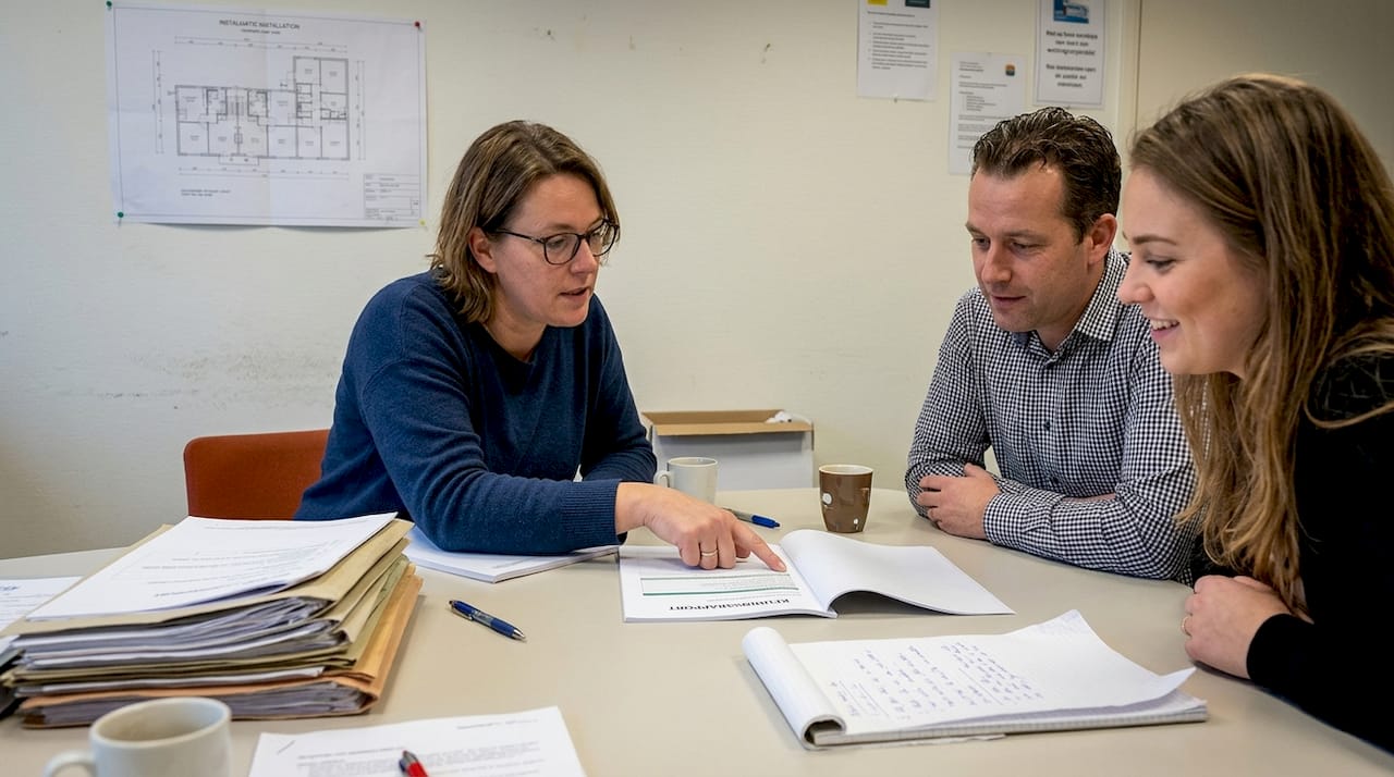 Het team bespreekt het onderhoudsrapport samen aan de vergadertafel op kantoor.