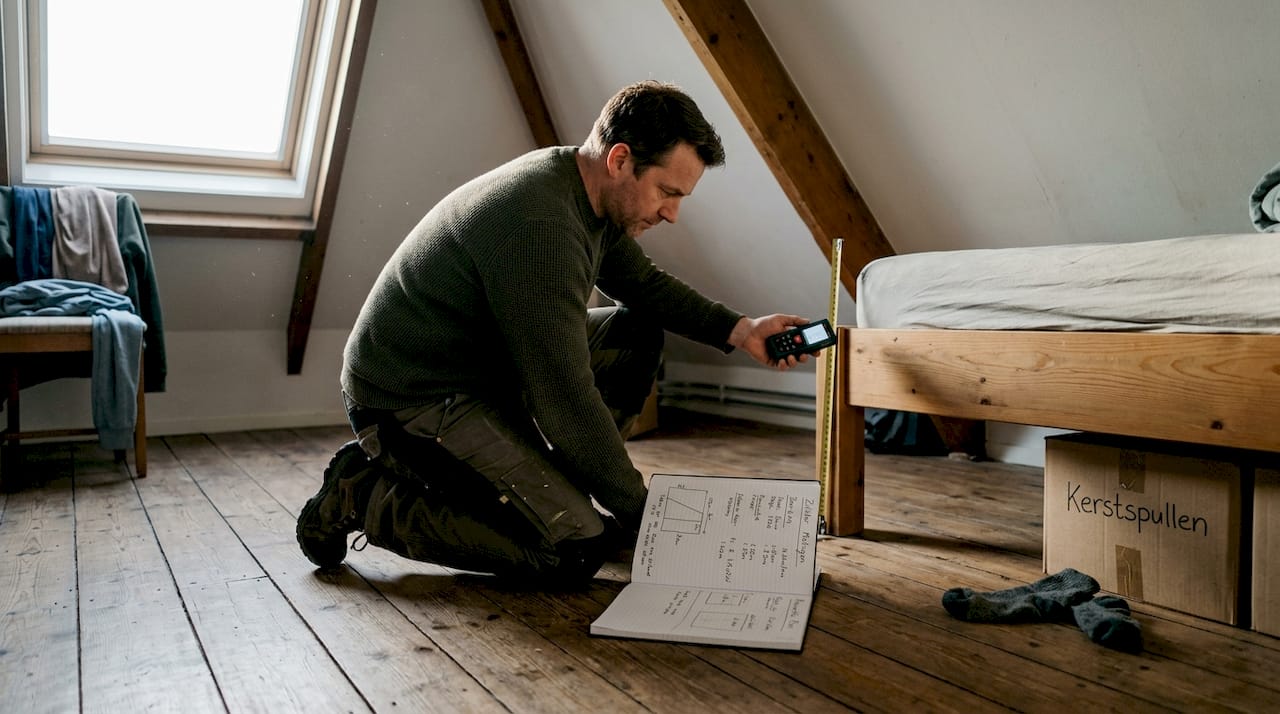 Man neemt maten van het schuine plafond in de slaapkamer