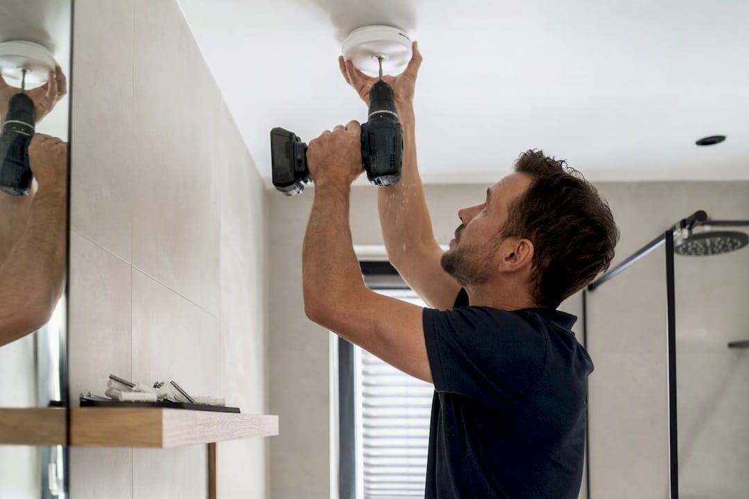 Het plafond boren om de bevestigingsplaat van de rookmelder te installeren