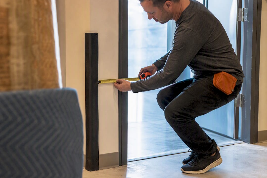 Installer measuring doorway clearance for artwork