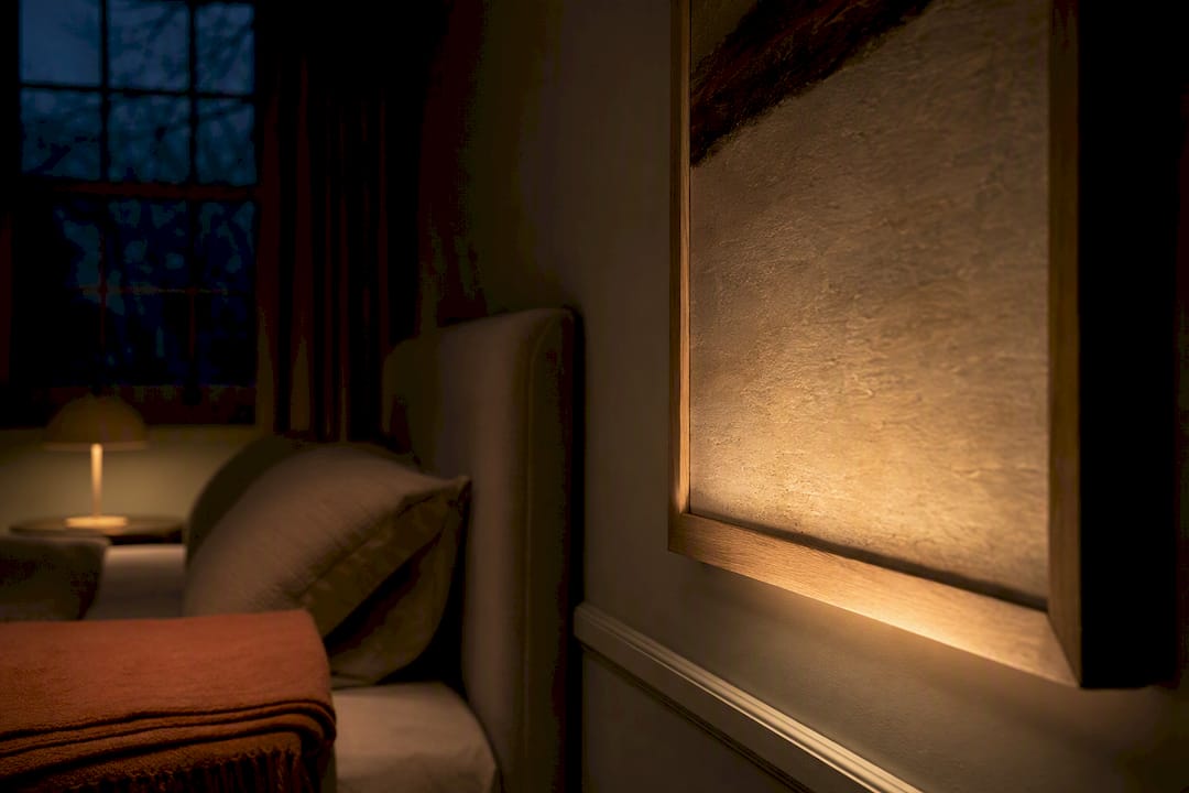 Warm picture light illuminating textured artwork
